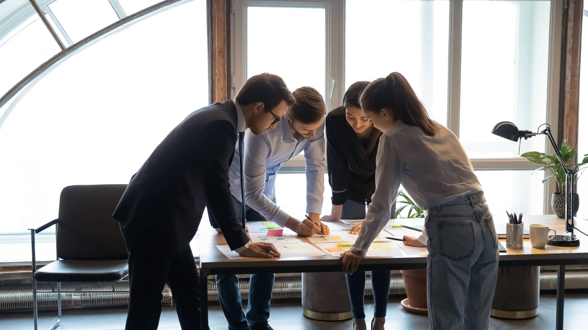 Team collaborating on a project while standing around a work table